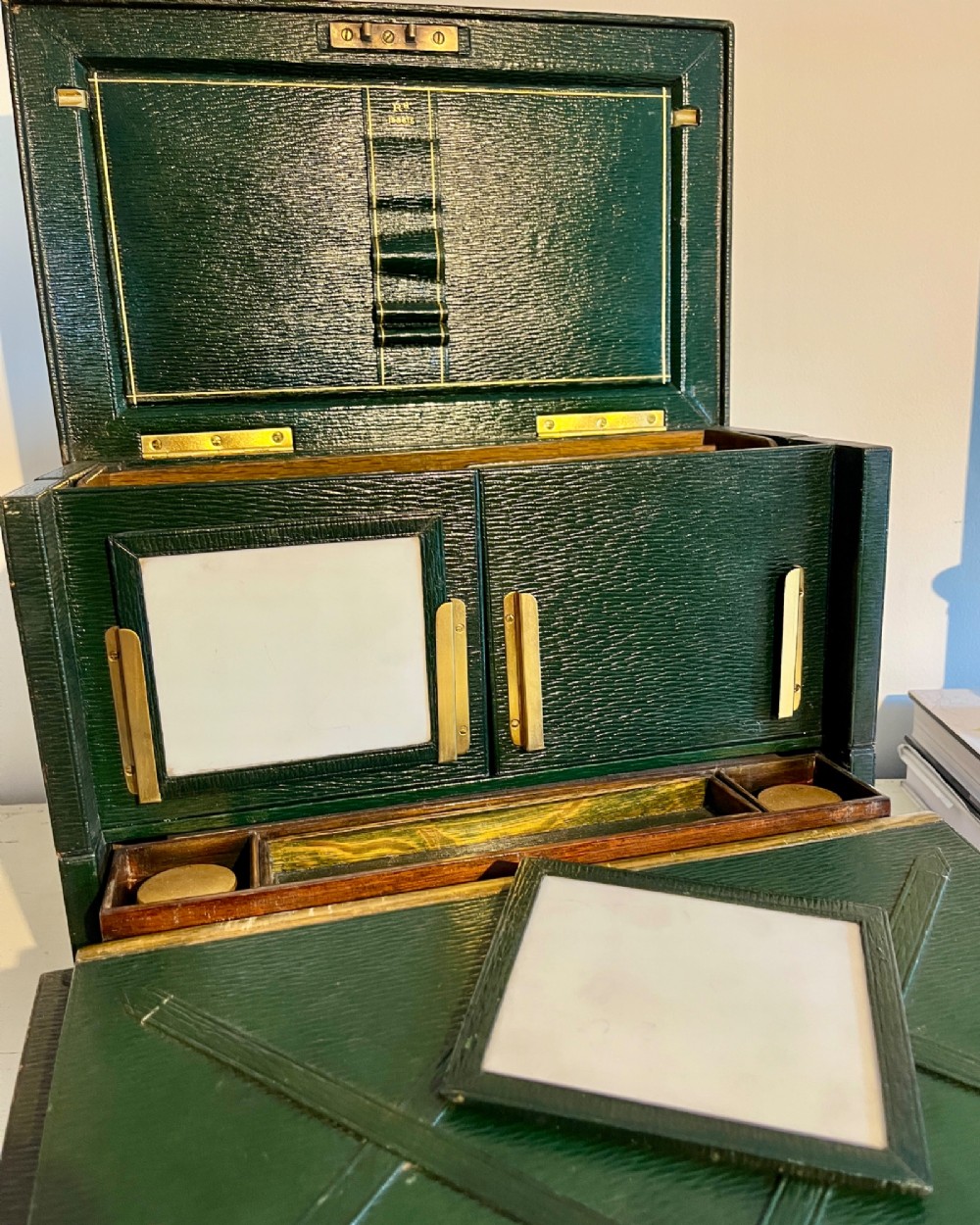 An open nineteenth-century dark green leather stationery box featuring brass fittings, interior memo panels, and compartmentalised sections. View IX