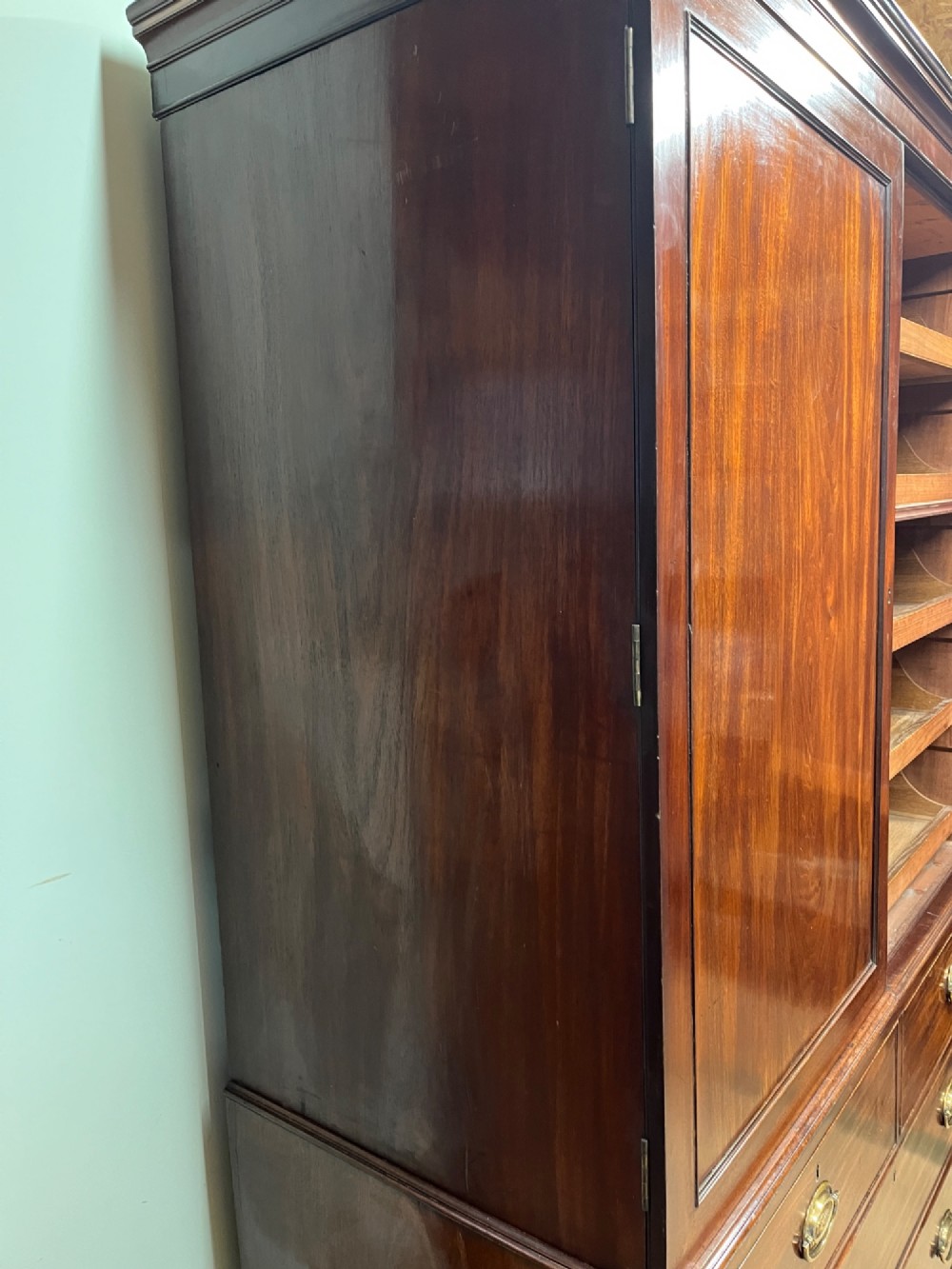 A Regency mahogany linen press featuring an upper two-door cupboard with flame veneer panels above a base of two short and two long drawers with brass handles. View VIII