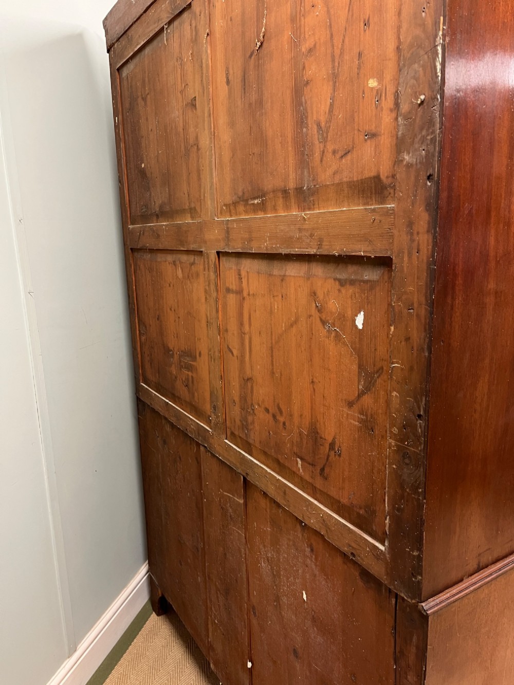 A Regency mahogany linen press featuring an upper two-door cupboard with flame veneer panels above a base of two short and two long drawers with brass handles. View XII