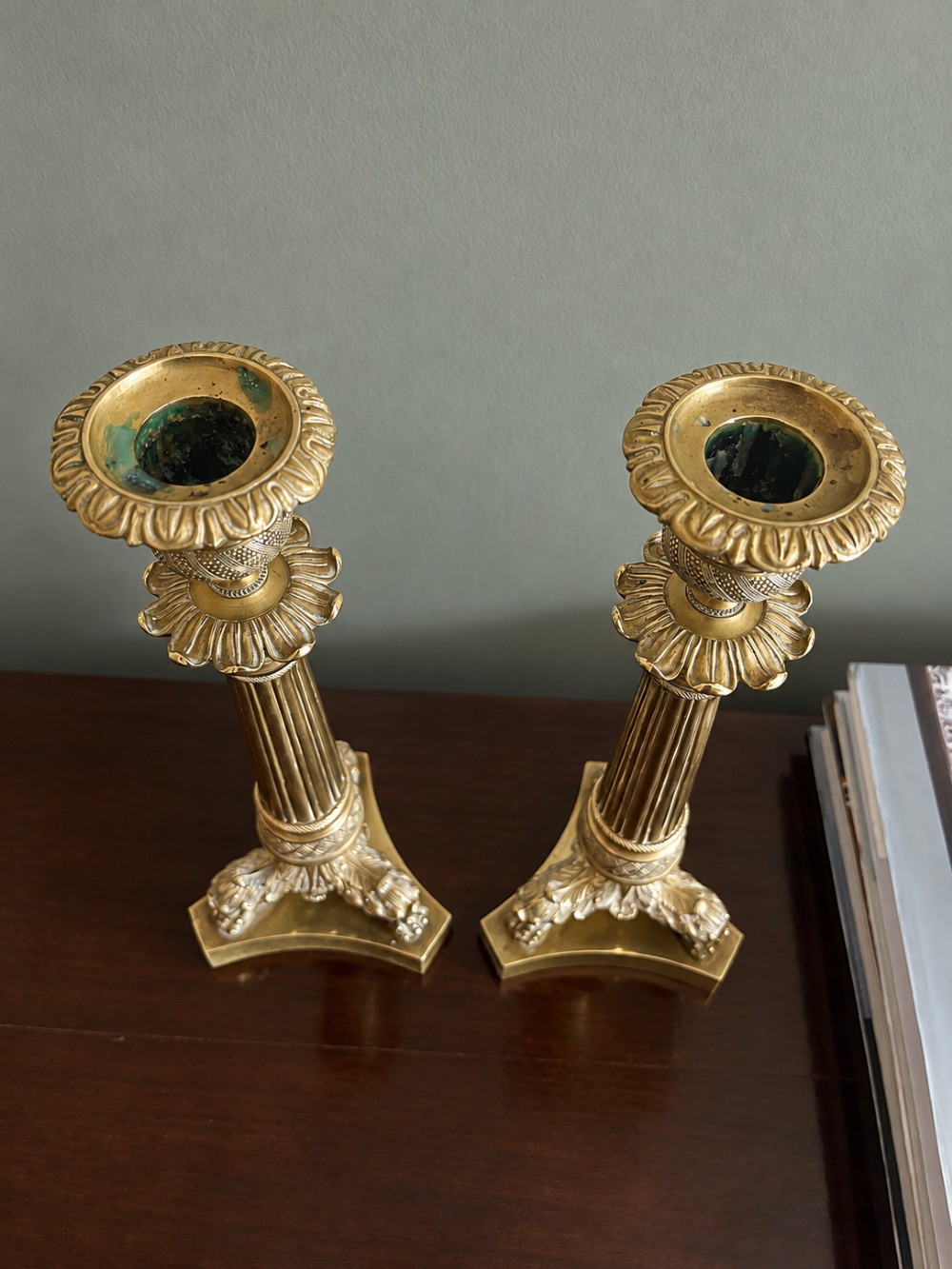 A pair of 19th-century Empire style cast brass candlesticks featuring fluted columns, engine-turned banding, and lion paw feet on tripartite bases. View IV