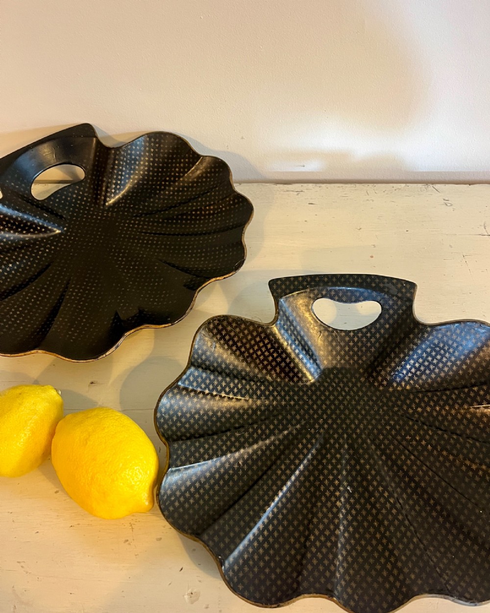 A pair of black lacquered shell-shaped trays decorated with a gold star pattern, fluted edges, and integrated cut-out handles. View II