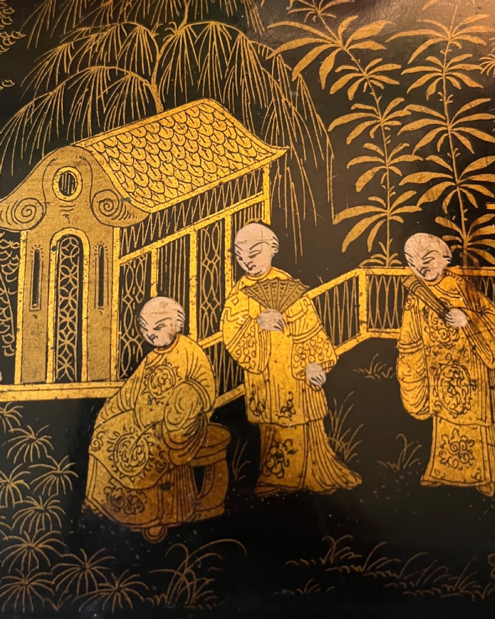 A rectangular black lacquered box decorated with detailed gold Chinoiserie scenes depicting figures, foliage, and pavilions. View IV