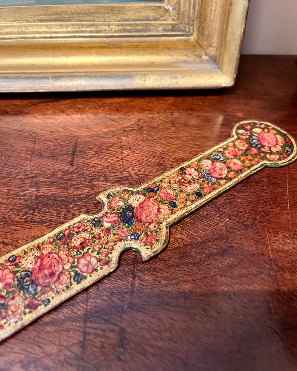 A 19th-century Kashmiri papier-mache letter opener featuring dense hand-painted polychrome floral decoration and gold detailing over a dark lacquered surface. View II