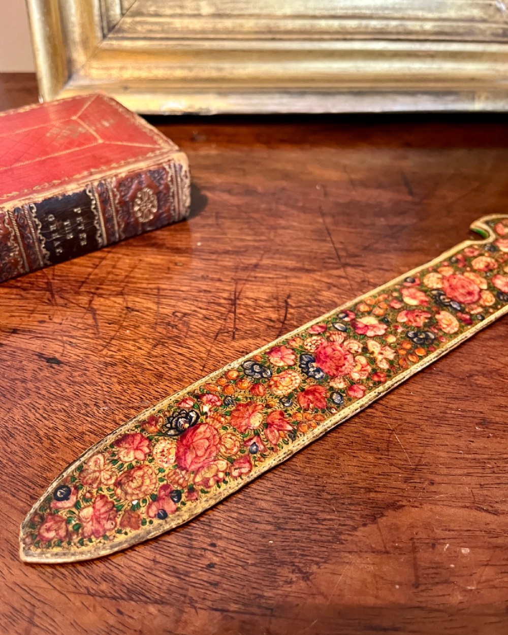 A 19th-century Kashmiri papier-mache letter opener featuring dense hand-painted polychrome floral decoration and gold detailing over a dark lacquered surface. View III