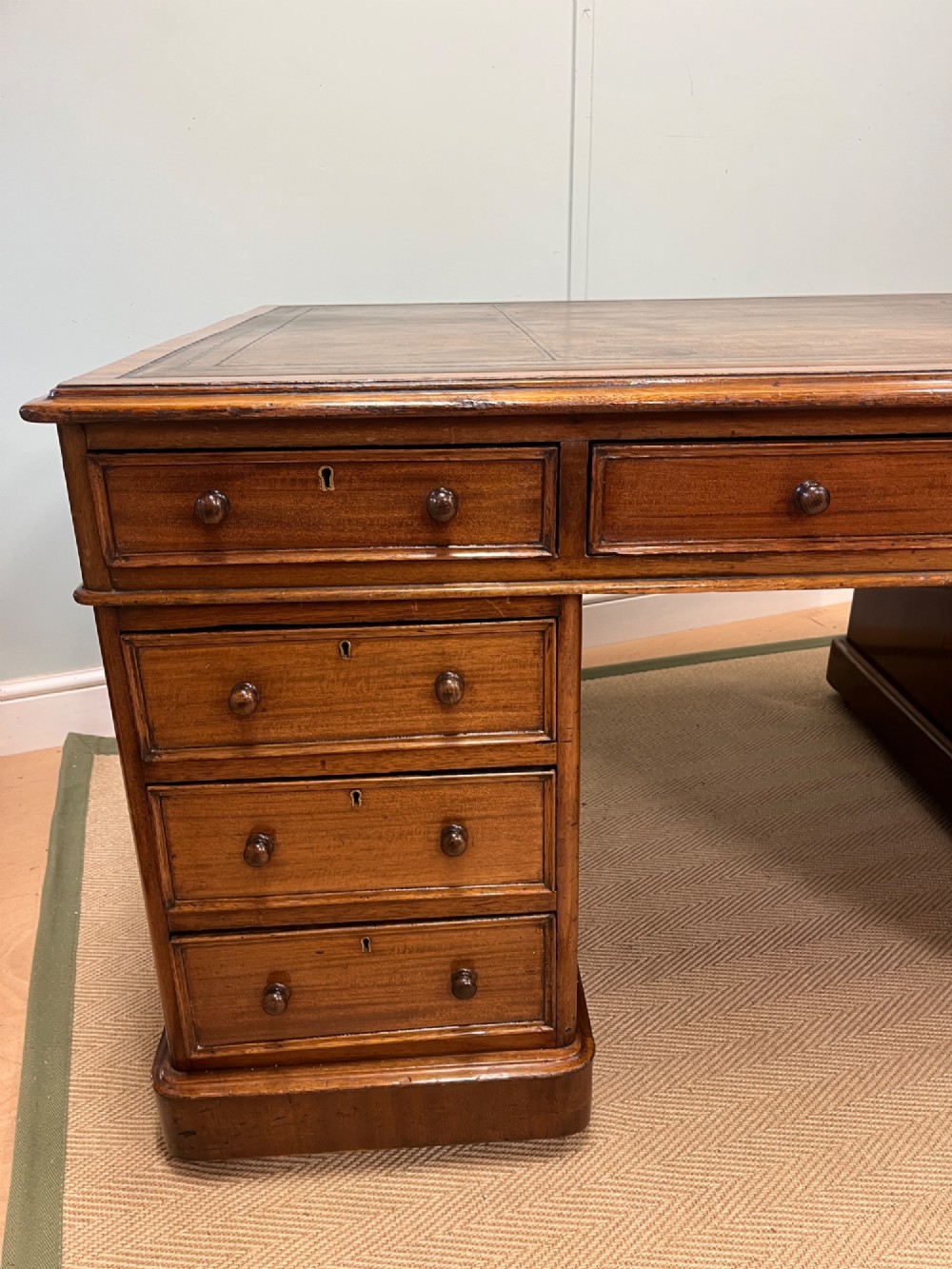 A nineteenth-century mahogany partners desk featuring an inset brown leather top, multiple drawers with turned wooden knobs, and twin pedestal bases. View II