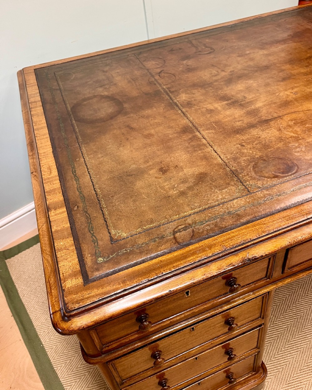 A nineteenth-century mahogany partners desk featuring an inset brown leather top, multiple drawers with turned wooden knobs, and twin pedestal bases. View IV