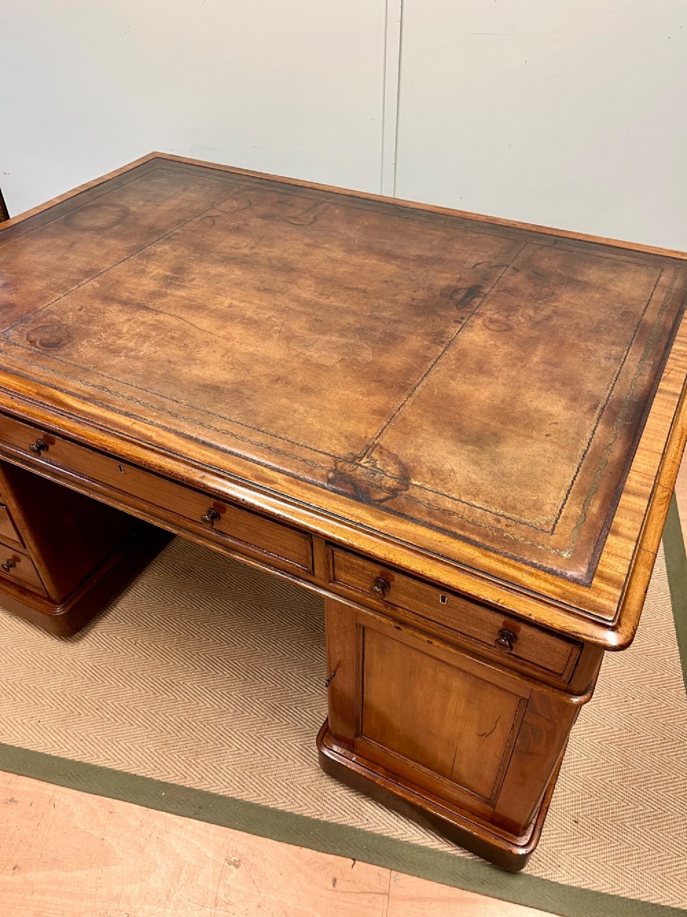 A nineteenth-century mahogany partners desk featuring an inset brown leather top, multiple drawers with turned wooden knobs, and twin pedestal bases. View V