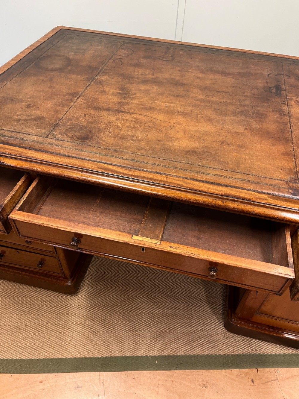 A nineteenth-century mahogany partners desk featuring an inset brown leather top, multiple drawers with turned wooden knobs, and twin pedestal bases. View VI