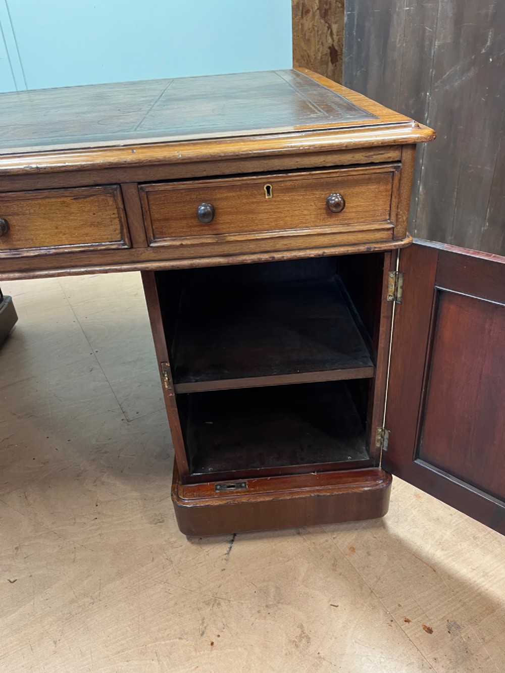 A nineteenth-century mahogany partners desk featuring an inset brown leather top, multiple drawers with turned wooden knobs, and twin pedestal bases. View VII