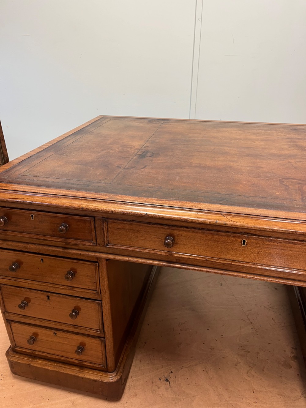A nineteenth-century mahogany partners desk featuring an inset brown leather top, multiple drawers with turned wooden knobs, and twin pedestal bases. View IX