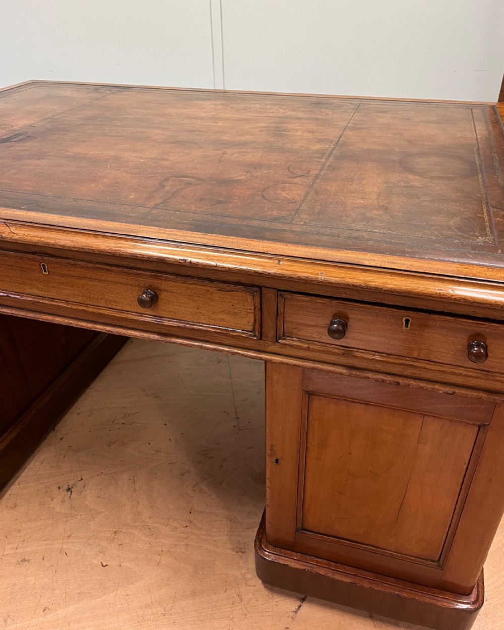 A nineteenth-century mahogany partners desk featuring an inset brown leather top, multiple drawers with turned wooden knobs, and twin pedestal bases. View X