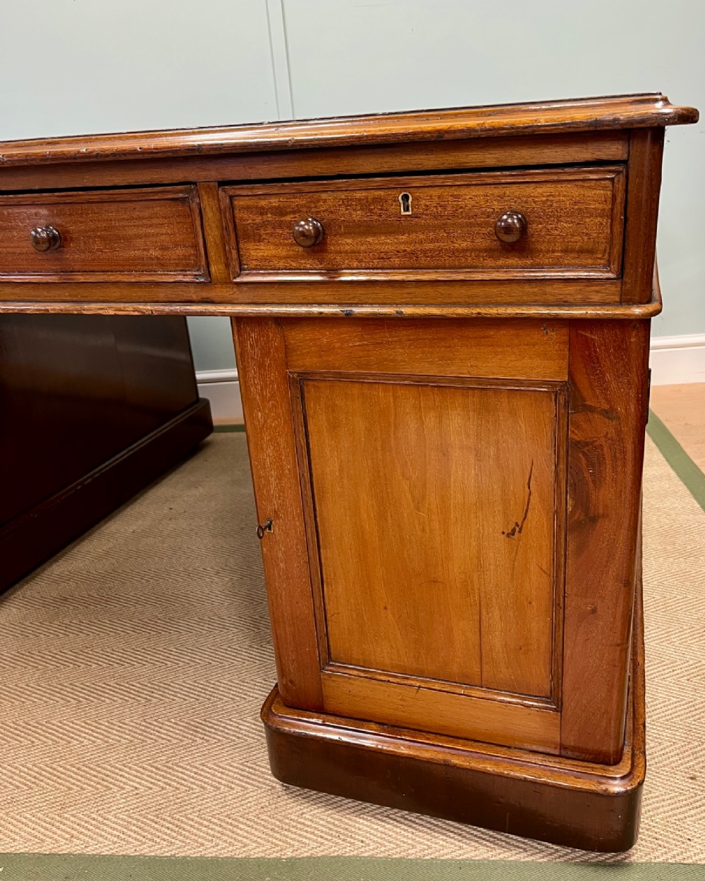 A nineteenth-century mahogany partners desk featuring an inset brown leather top, multiple drawers with turned wooden knobs, and twin pedestal bases. View XII