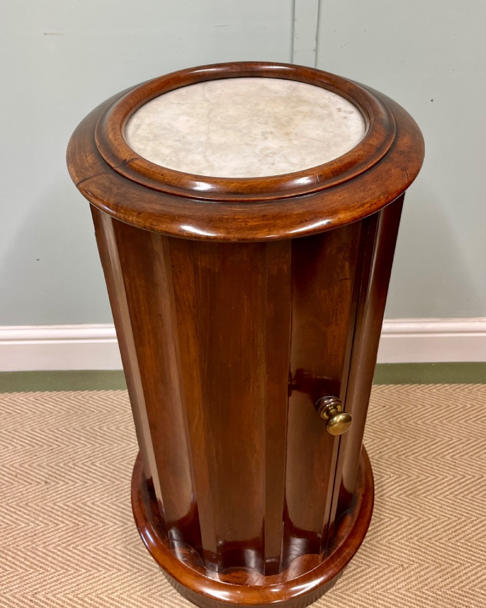A 19th-century cylindrical dark mahogany pot cupboard featuring vertical fluting, a circular inset marble top, a single curved door, and a brass knob. View II