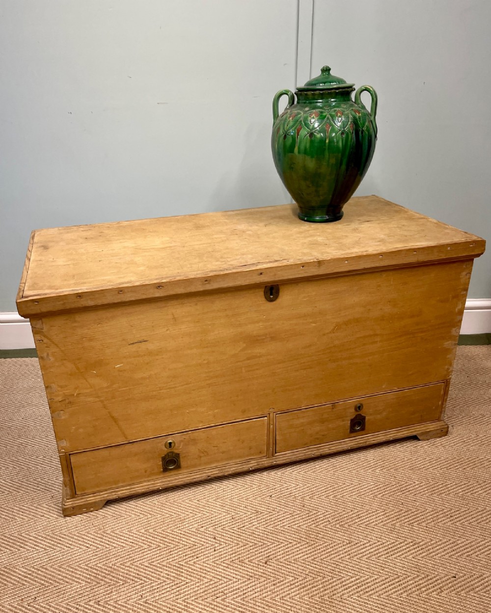 A 19th-century natural pine mule chest featuring a hinged top lid and two bottom drawers fitted with brass keyhole escutcheons. View II