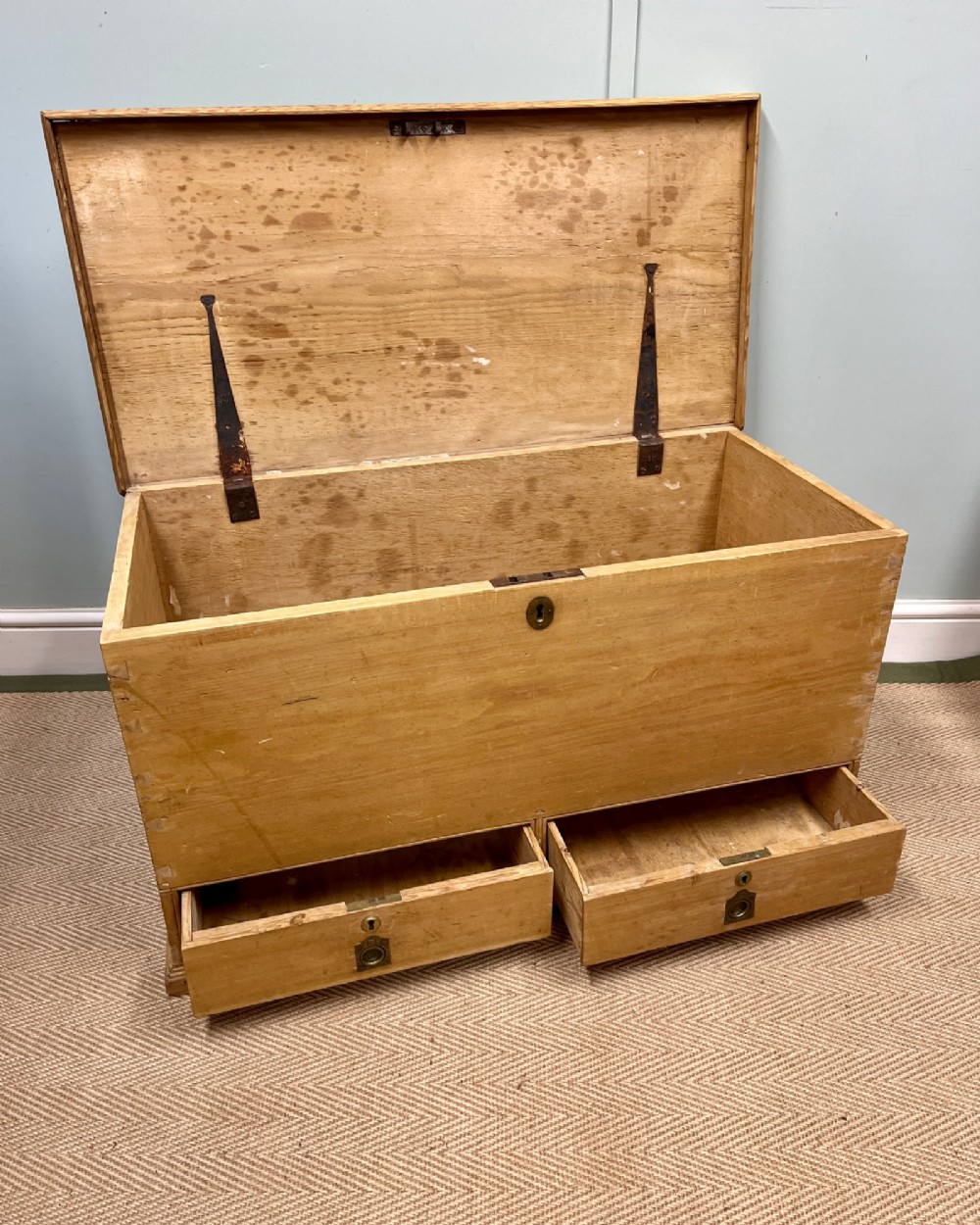 A 19th-century natural pine mule chest featuring a hinged top lid and two bottom drawers fitted with brass keyhole escutcheons. View III