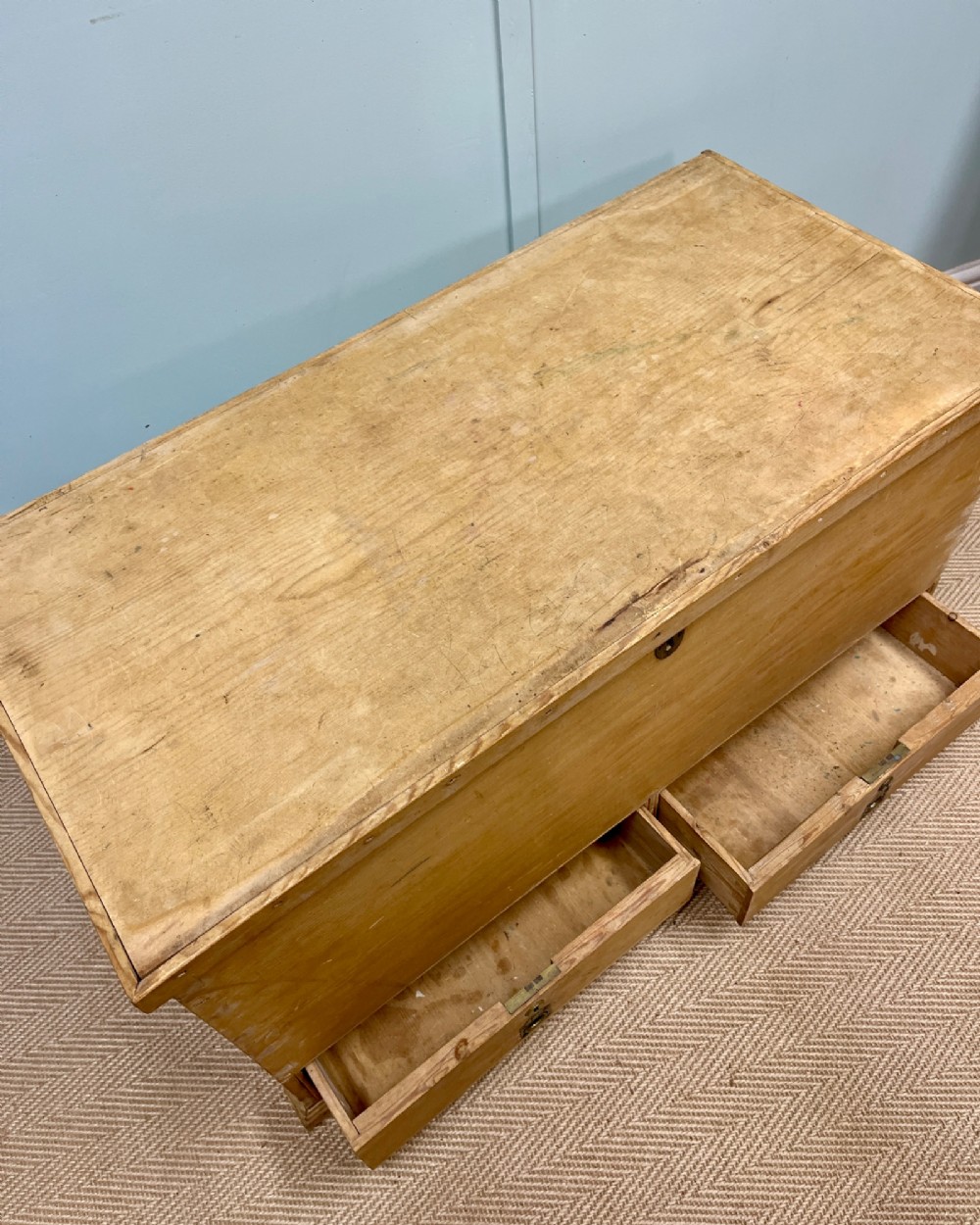 A 19th-century natural pine mule chest featuring a hinged top lid and two bottom drawers fitted with brass keyhole escutcheons. View V