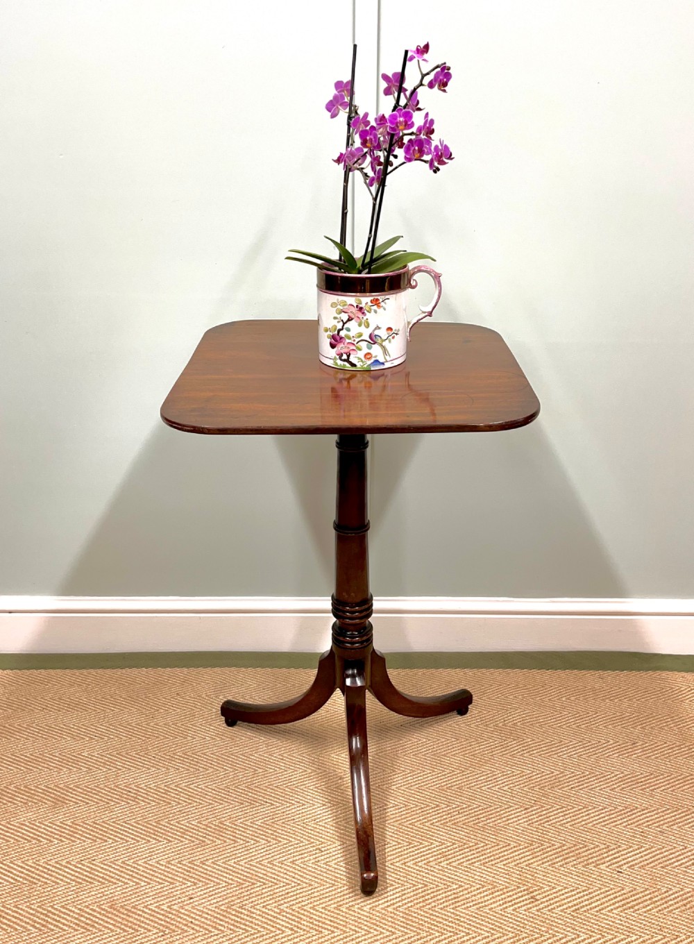 A 19th-century mahogany snap-top side table featuring a square top with rounded corners, a turned central column, and three splayed legs.