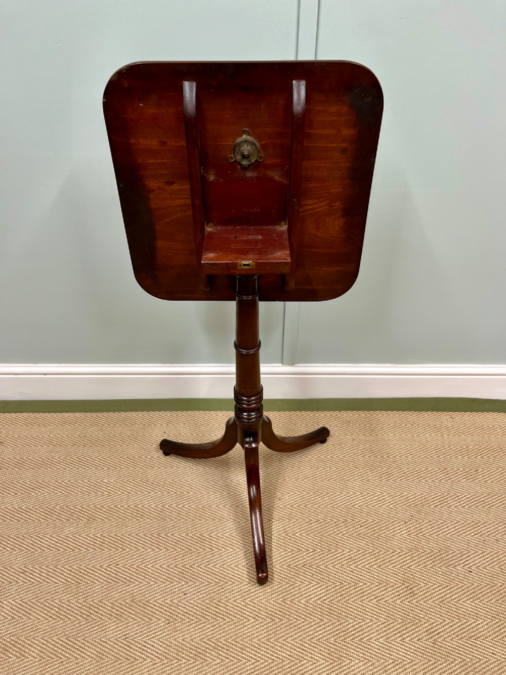 A 19th-century mahogany snap-top side table featuring a square top with rounded corners, a turned central column, and three splayed legs. View II