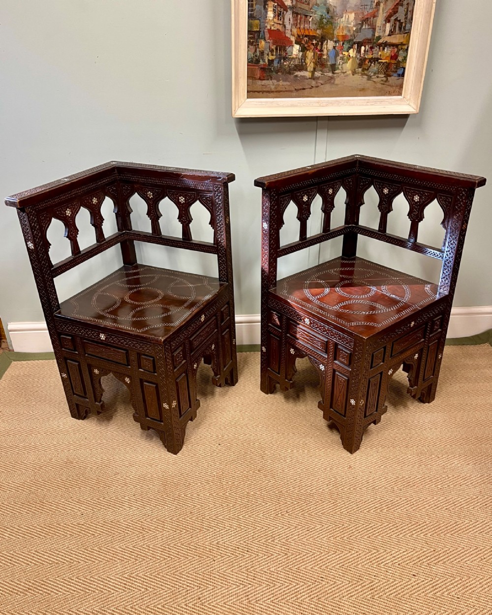 A pair of dark wood early 20th-century Moorish corner tables featuring geometric bone inlay and carved mashrabiya arch galleries.