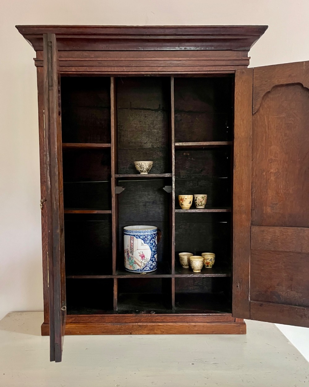 An eighteenth-century dark oak wall cupboard featuring twin arched fielded panel doors and prominent brass H-hinges. View III