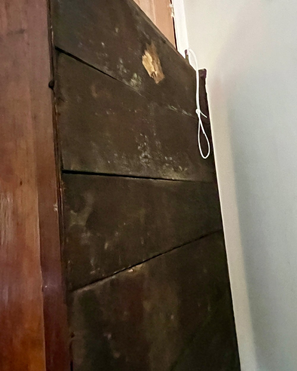 An eighteenth-century dark oak wall cupboard featuring twin arched fielded panel doors and prominent brass H-hinges. View VI