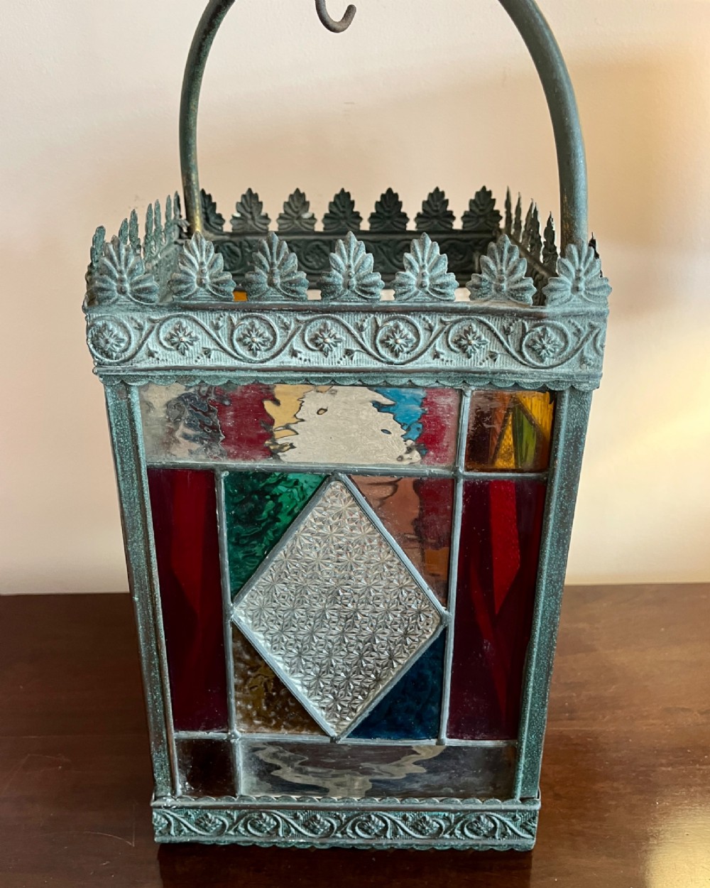 A nineteenth-century four-sided brass hall lantern featuring multi-coloured stained glass panels and a decorative cresting rim suspended from an arched handle. View IV