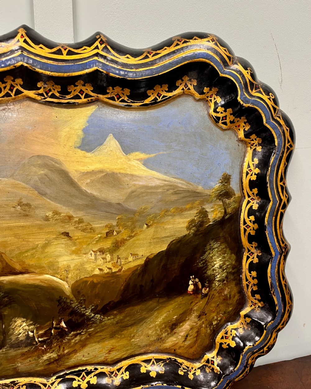 A black scalloped Regency papier-mache tray featuring a hand-painted mountain landscape encircled by a gilded decorative border. View III