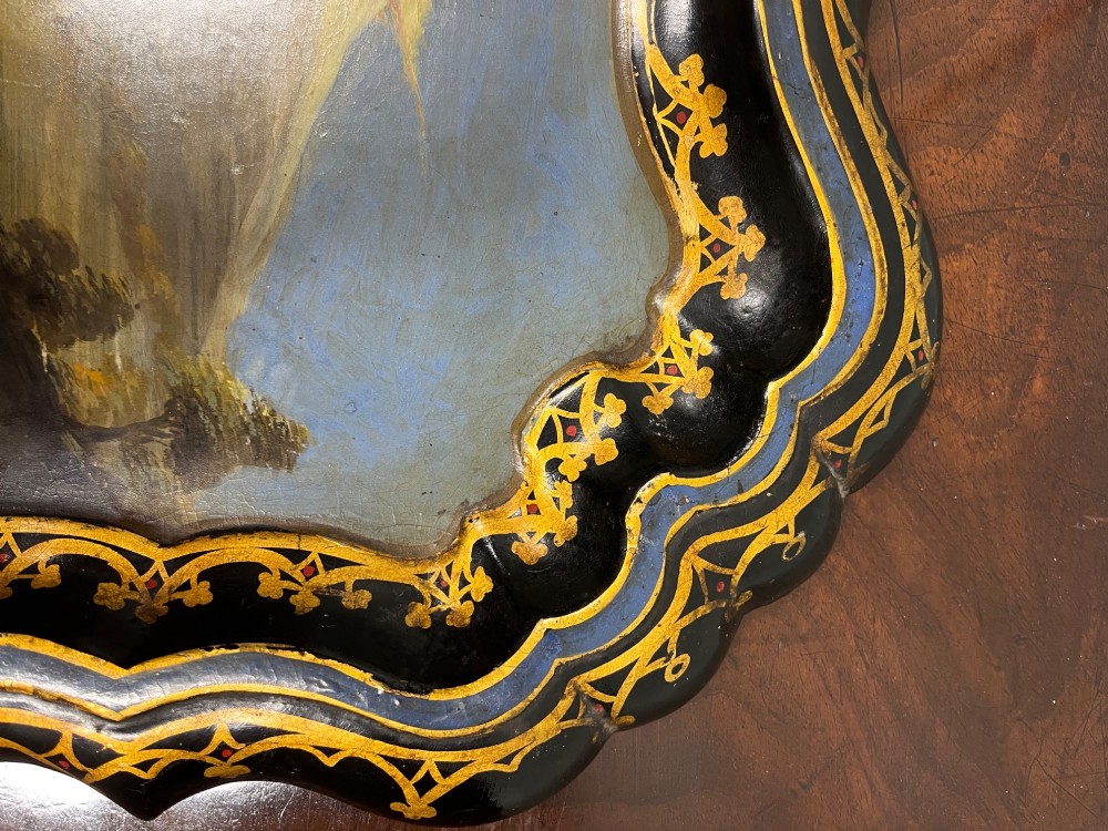 A black scalloped Regency papier-mache tray featuring a hand-painted mountain landscape encircled by a gilded decorative border. View V
