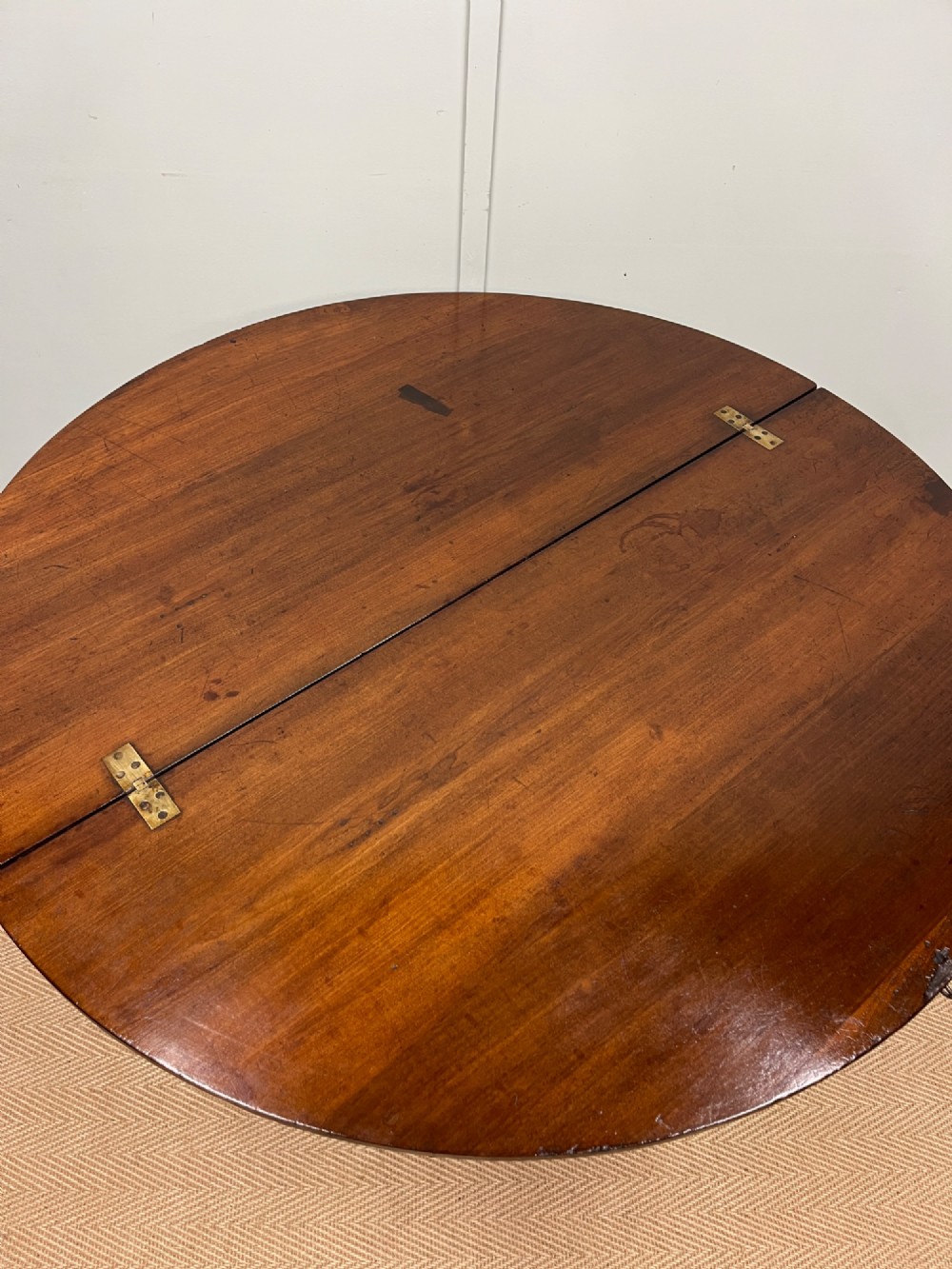 A circular 19th-century mahogany coaching table featuring a central hinged seam and brass hardware on turned legs. View II