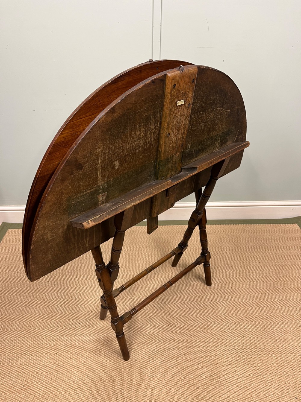 A circular 19th-century mahogany coaching table featuring a central hinged seam and brass hardware on turned legs. View IV