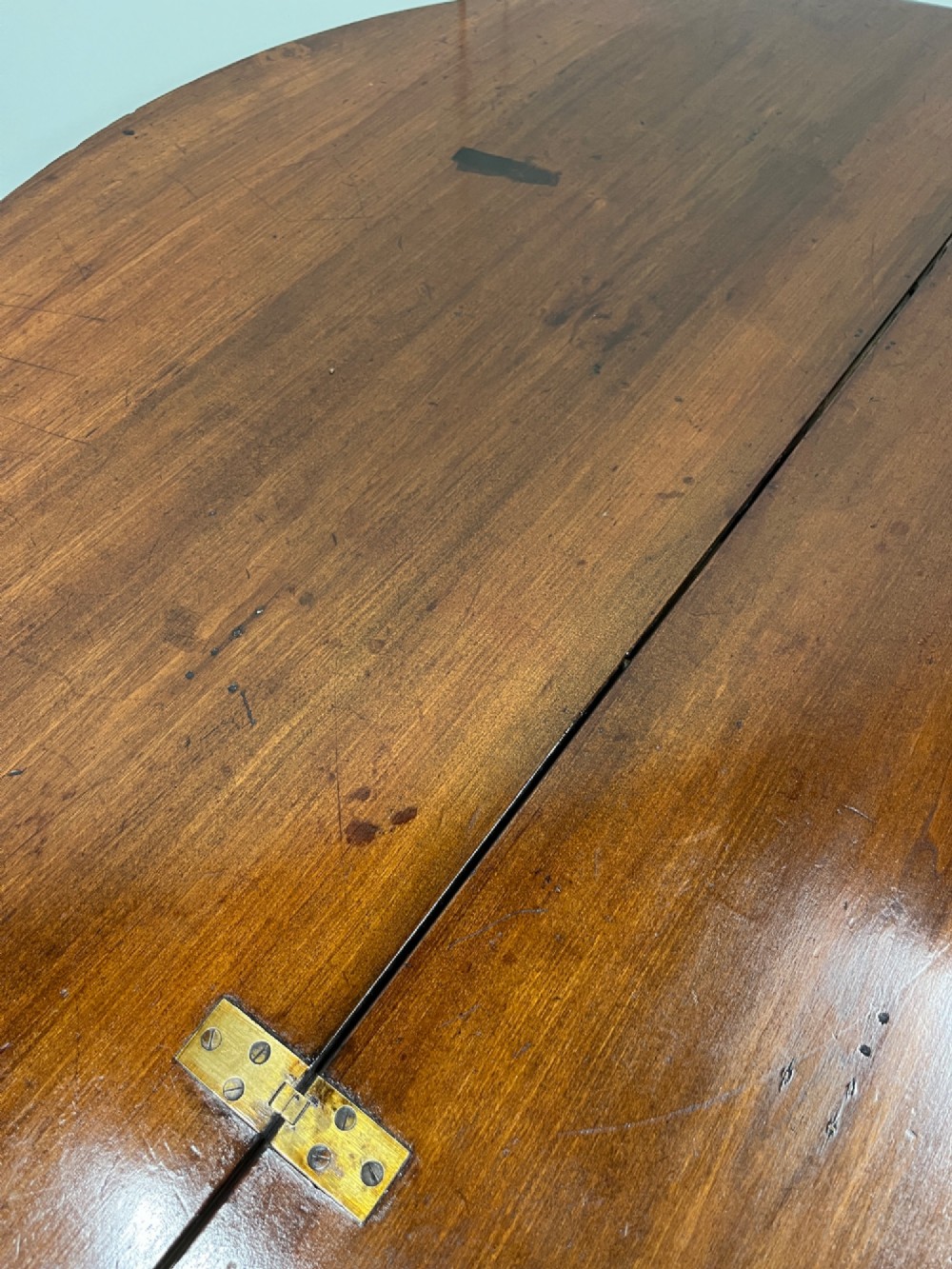 A circular 19th-century mahogany coaching table featuring a central hinged seam and brass hardware on turned legs. View V