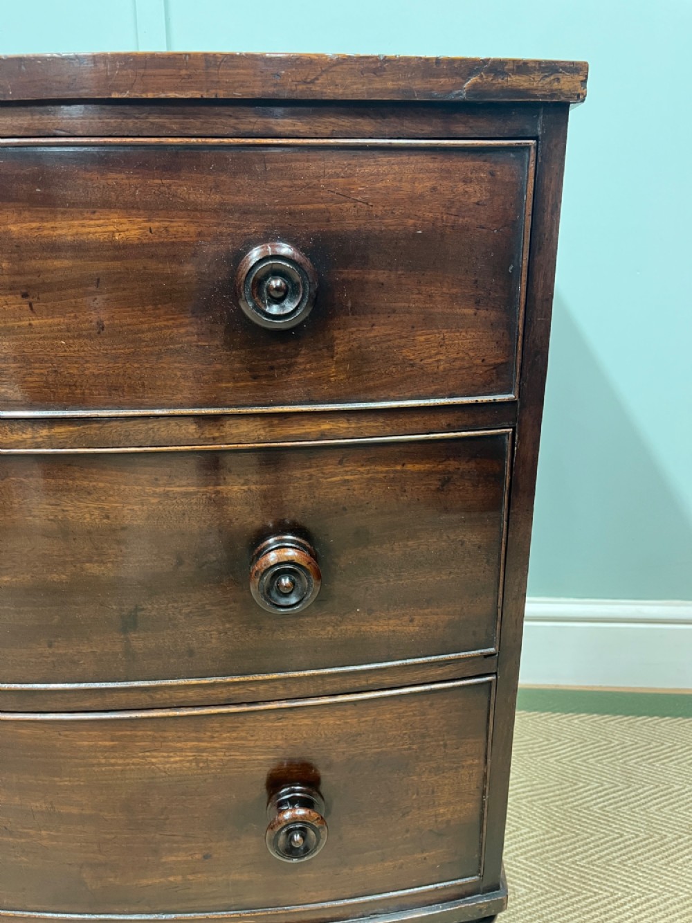 A 19th-century mahogany bowfront chest of drawers featuring three graduated drawers with turned wooden handles. View VII