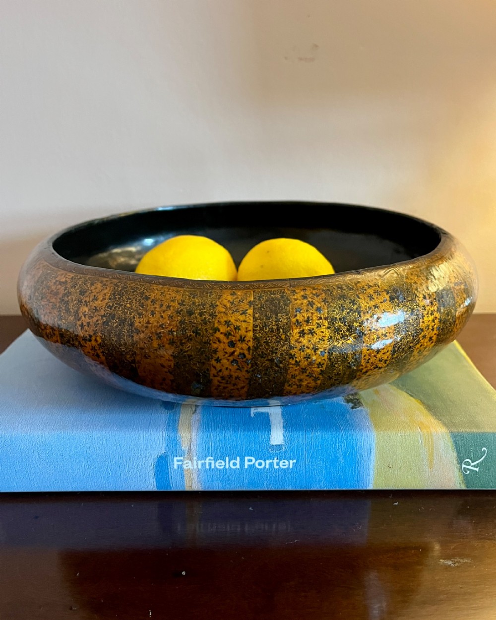A shallow rounded 19th-century Kashmiri bowl decorated with vertical gold and black floral lacquer patterns and a dark lacquered interior.
