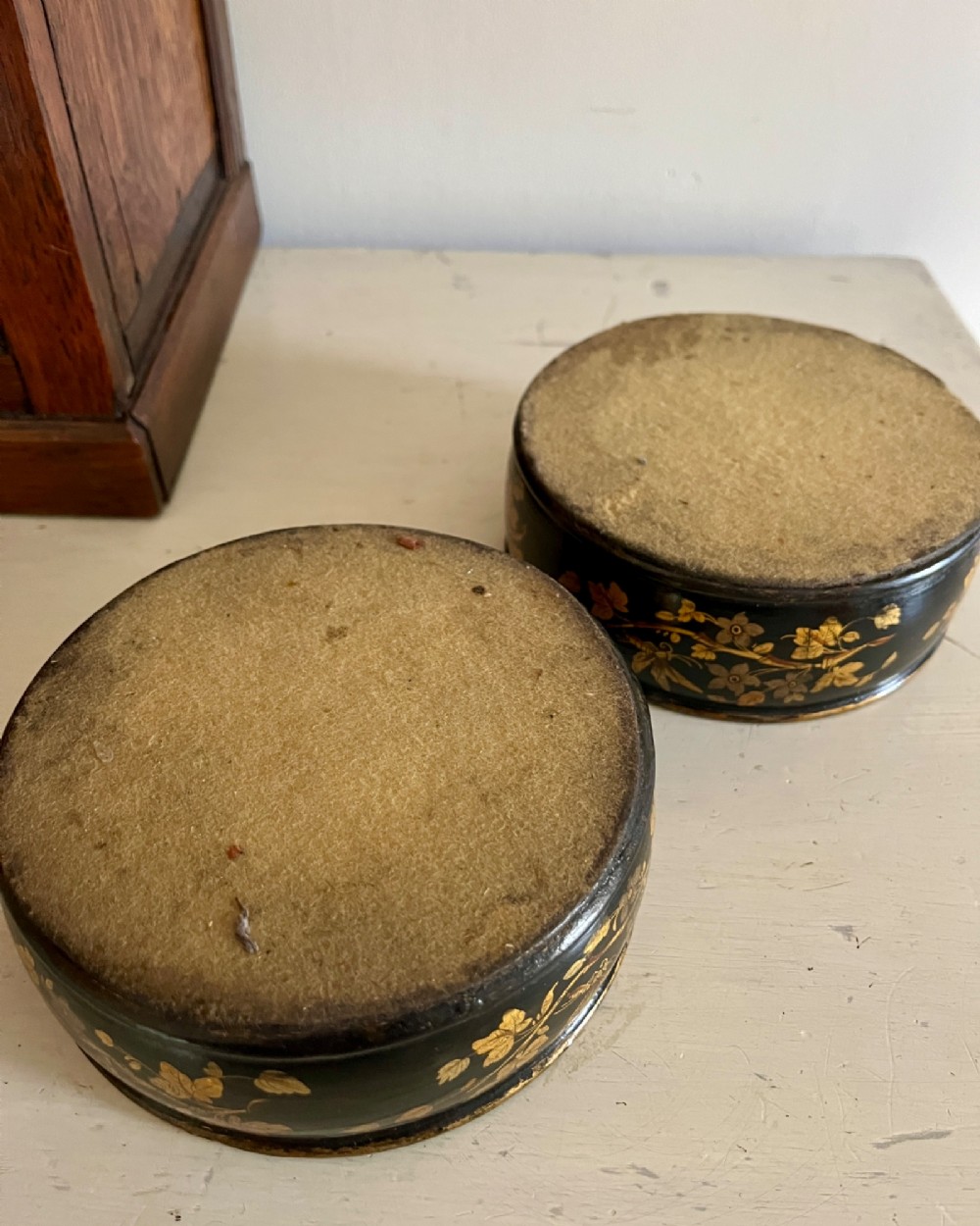 A pair of circular black lacquered papier-mache wine coasters decorated with hand-painted gold botanical and dragonfly motifs. View IV