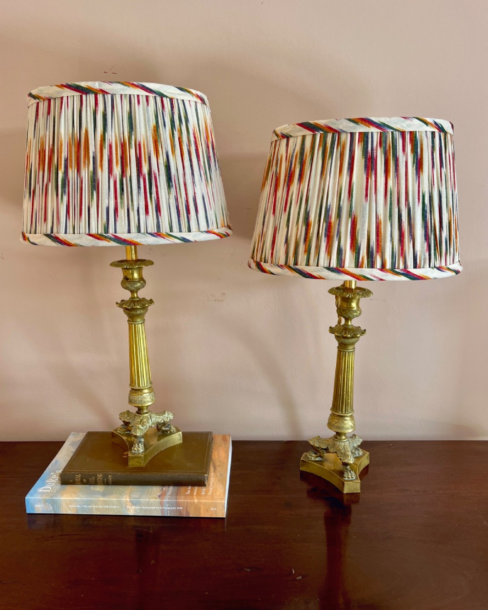 A pair of 19th-century fluted brass table lamps featuring claw feet bases and colourful pleated ikat fabric shades.