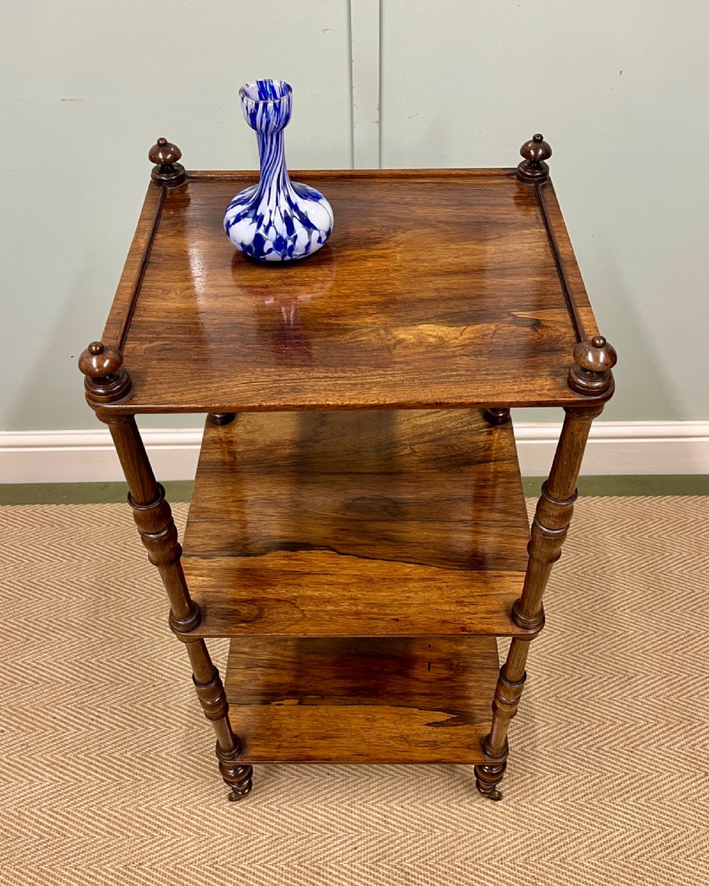 A 19th-century rosewood three-tier etagere featuring turned spindle corner posts, top finials, and brass castors on the feet. View III