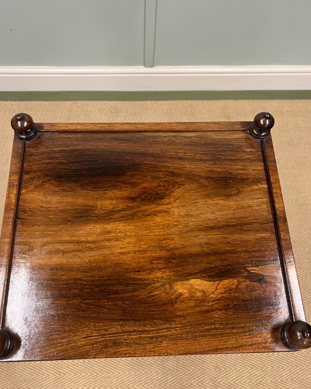A 19th-century rosewood three-tier etagere featuring turned spindle corner posts, top finials, and brass castors on the feet. View V