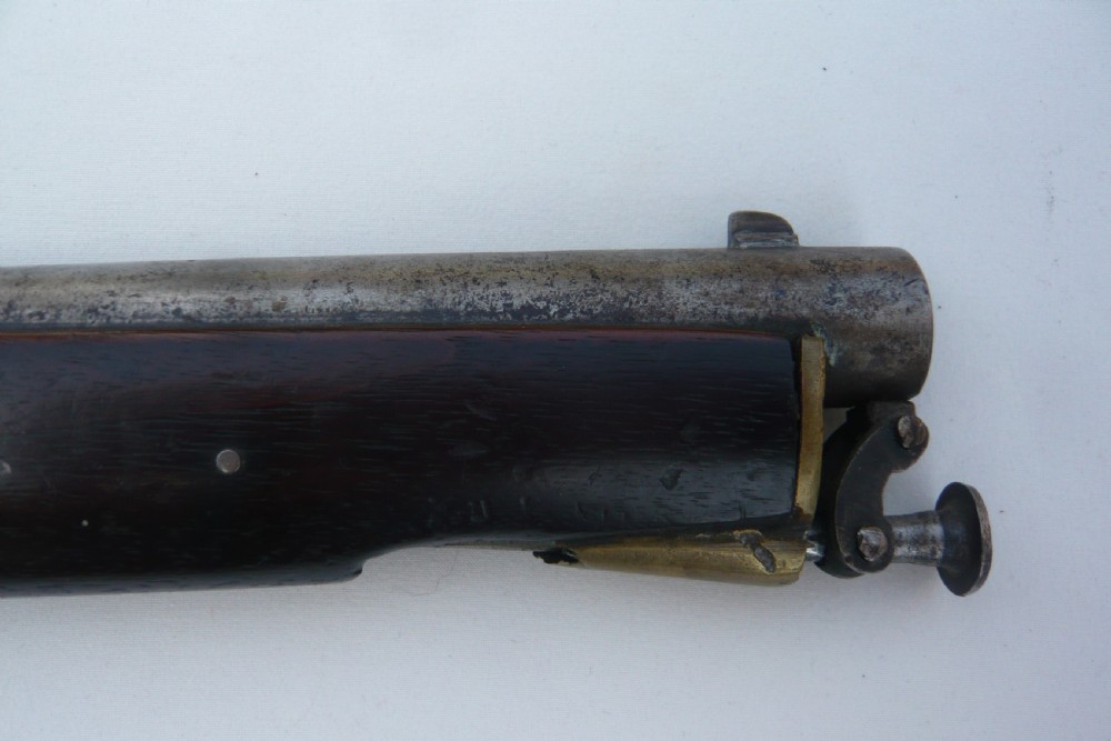 A 19th-century military percussion pistol featuring a dark hardwood stock, steel barrel, lockplate mechanism, brass trigger guard, and captive ramrod. View III