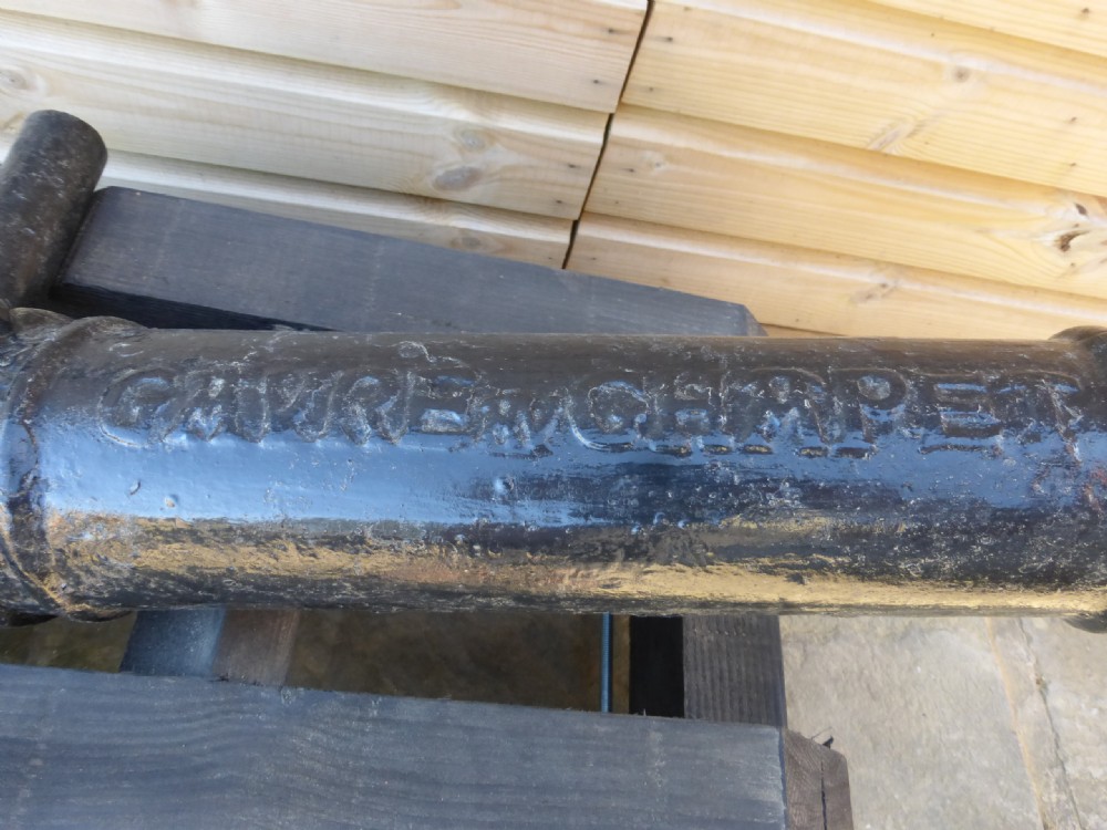 A 19th-century French cast iron cannon barrel with raised mouldings and dolphin handles, mounted on a dark timber wheeled carriage. View II