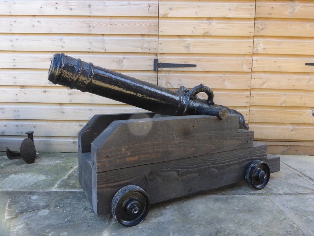 A 19th-century French cast iron cannon barrel with raised mouldings and dolphin handles, mounted on a dark timber wheeled carriage. View VII
