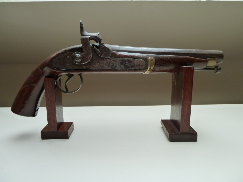 A 19th-century single-barrel percussion cap pistol featuring a dark wood stock, steel lock mechanism, and brass mountings.