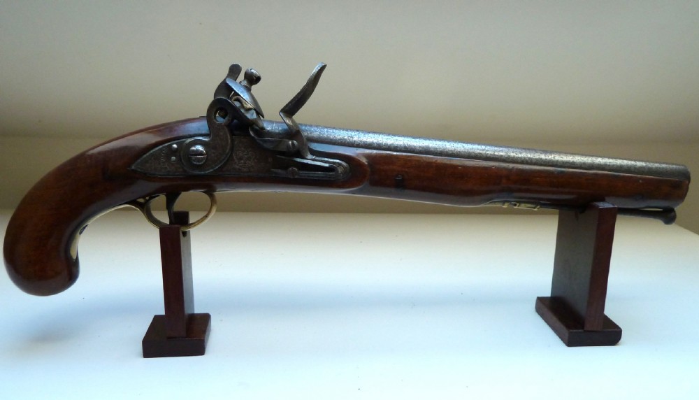 An antique British long-barrelled flintlock dragoon pistol featuring a polished walnut stock, steel barrel, steel lock mechanism, and brass fittings.