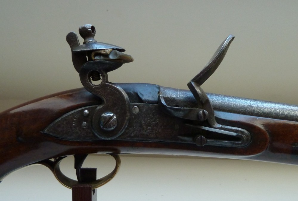 An antique British long-barrelled flintlock dragoon pistol featuring a polished walnut stock, steel barrel, steel lock mechanism, and brass fittings. View III