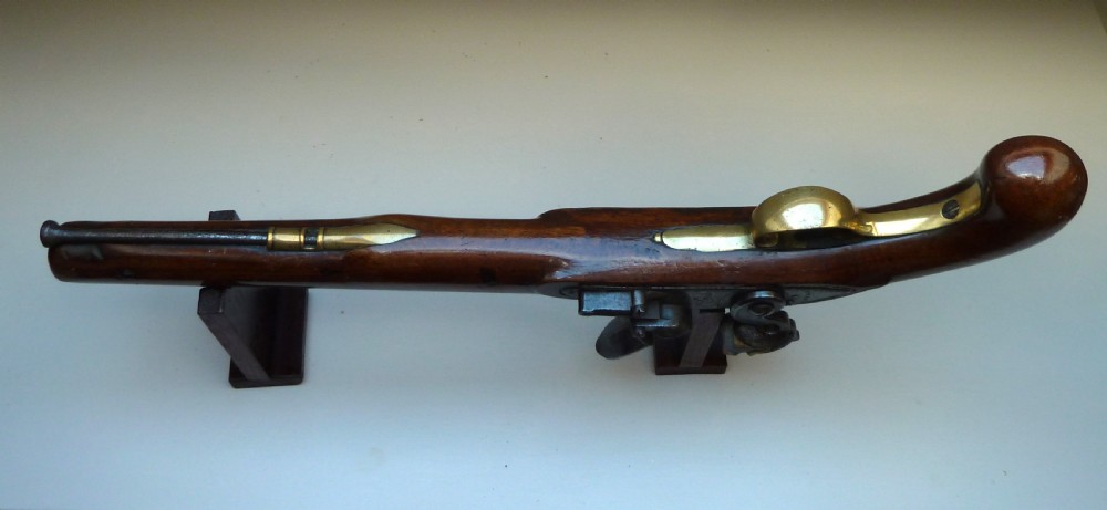 An antique British long-barrelled flintlock dragoon pistol featuring a polished walnut stock, steel barrel, steel lock mechanism, and brass fittings. View VII