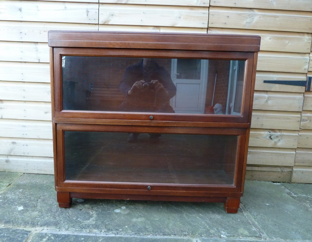 An Art Deco two-tier modular wood sectional bookcase featuring glass up-and-over doors and square block feet. View II