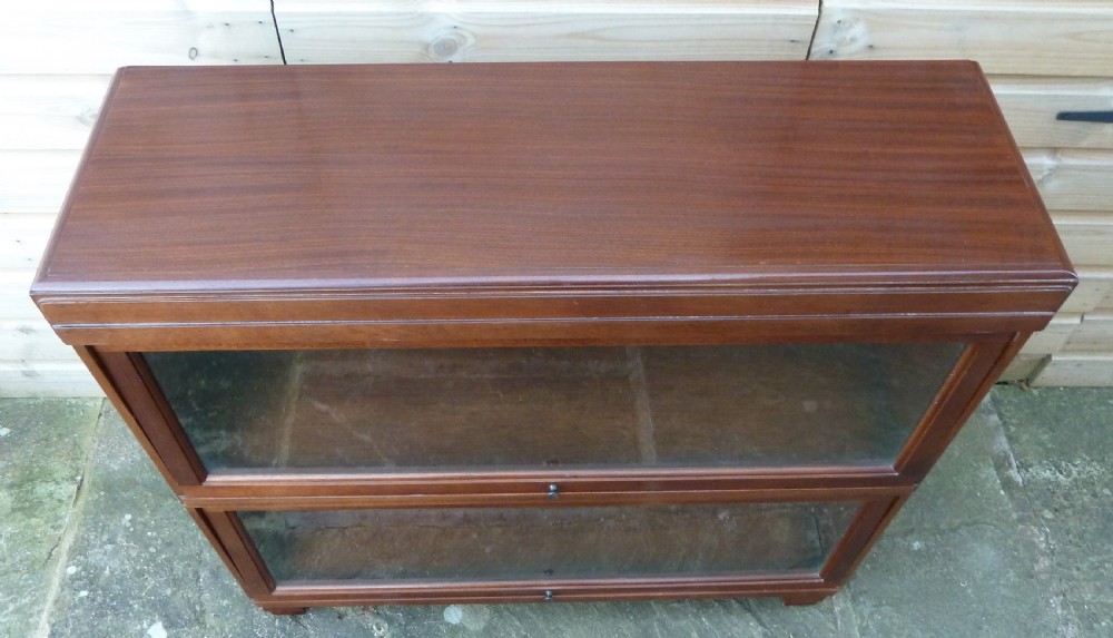 An Art Deco two-tier modular wood sectional bookcase featuring glass up-and-over doors and square block feet. View III
