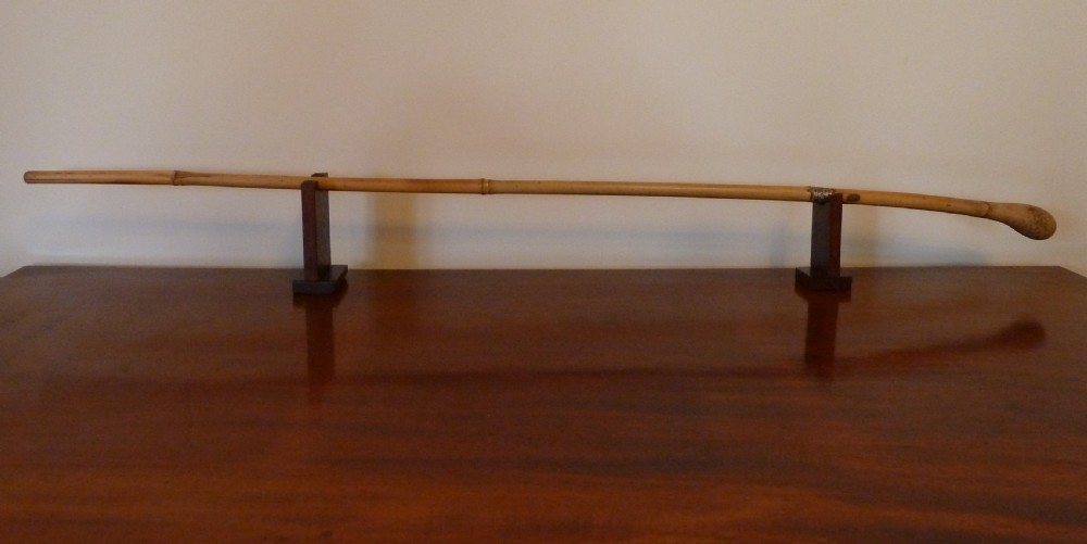 An antique bamboo swordstick shown partially unsheathed to reveal a concealed steel blade, featuring a natural bamboo handle and metal collar band. View III