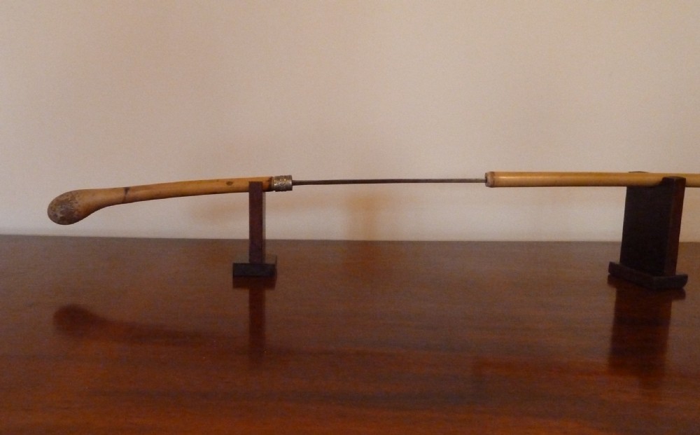 An antique bamboo swordstick shown partially unsheathed to reveal a concealed steel blade, featuring a natural bamboo handle and metal collar band. View V