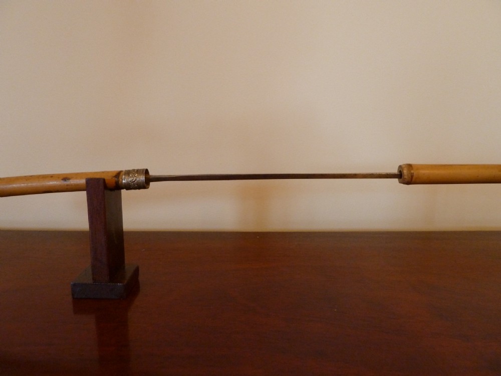 An antique bamboo swordstick shown partially unsheathed to reveal a concealed steel blade, featuring a natural bamboo handle and metal collar band. View VI
