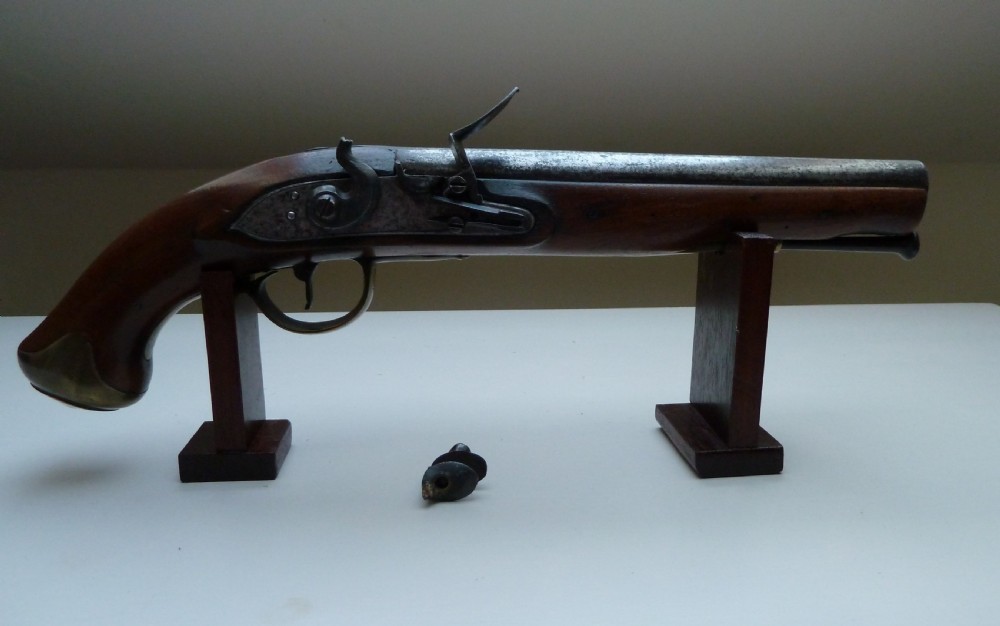 A pair of early 19th-century flintlock duelling pistols featuring contoured wooden stocks, brass sideplates, and steel barrels. View IX